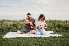 a man and woman are sitting on a blanket with a baby in their arms while they hold each other