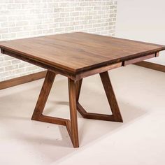 a wooden table sitting in front of a brick wall with two legs on each side