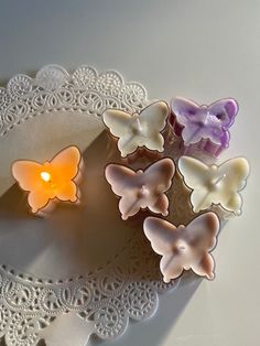 small candles with butterflies on them sitting on a doily next to a lace doily