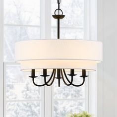 a chandelier hanging from the ceiling in a dining room with white walls and windows