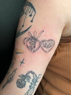 a woman's arm with tattoos on it and two hearts in the shape of heart