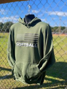 "Introducing the \"Stars and Strikes\" Softball Hoodie in Military Green with White Stars and black stripes Step up to the plate in style and show your love for the game and your country! This shirt features bold white stars on a military green background, with \"Softball\" written in a distressed font to represent the determination and hard work of dedicated softball players. Crafted from a soft and comfortable 50/50 cotton/polyester blend pullover sweatshirt, this hoodie is perfect for wearing Softball Mom, Softball Sweatshirt, Softball Outfits, Distressed Font, Softball Coach, Country Wear, Girls Softball, Softball Players, Easy Trendy Outfits