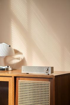 an old radio sitting on top of a wooden cabinet next to a lamp and wall