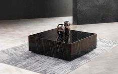 a black marble coffee table with two vases sitting on it's side and an area rug in front of it