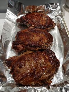 three steaks sitting on top of aluminum foil