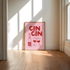 a pink poster with the words gin on it in front of a window and wooden floor