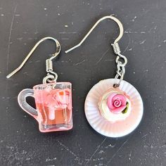 two pink cupcakes are sitting next to each other on a plate with silver earwires