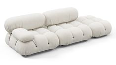 a white couch with multiple pillows on it's back and arms, sitting in front of a white background