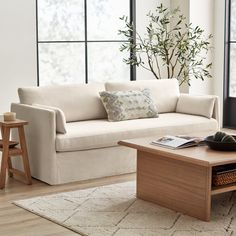 a living room with a couch, coffee table and large windows in the back ground