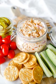 a plate with crackers, tomatoes, cucumbers and pickles