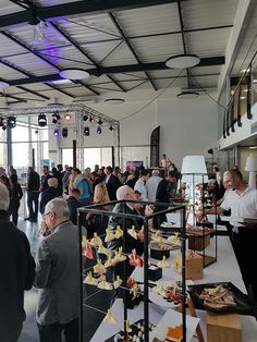 a large group of people are standing in a room with food on tables and chairs