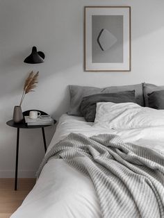 a bed with white sheets and grey blankets