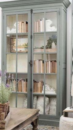 a book case with many books on it in a room filled with furniture and flowers