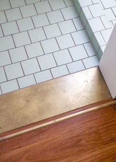 a bathroom with white tile and wood flooring next to a shower door that has the word forte written on it