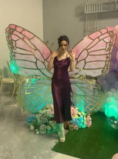 a woman in a purple dress standing next to a giant butterfly