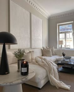 a living room filled with furniture and a large white couch next to a table on top of a hard wood floor