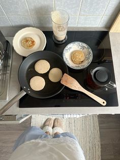 the person is cooking on the stove with his feet up in front of him and there are two pans full of food