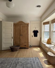 an empty room with wooden floors and white walls, has a blue rug on the floor