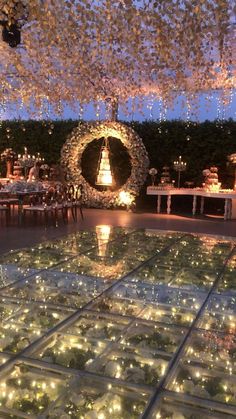 an indoor wedding reception with lights on the dance floor and flowers hanging from the ceiling