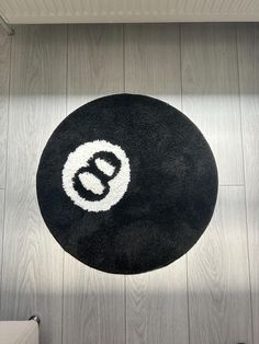 a black and white rug with the letter e on it in front of a wooden floor