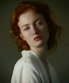 a woman with red hair is looking at the camera