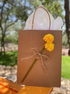 a brown paper bag with a yellow flower on it and some string attached to the handle