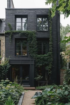 a black house with lots of plants growing on it