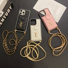 three cell phones are laying next to each other on a table with gold chains around them