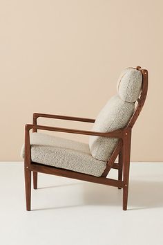 a chair with a cushion on it sitting in front of a beige wall and white floor