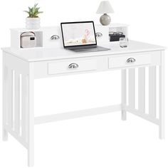 a laptop computer sitting on top of a white desk next to a potted plant