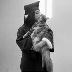 a woman wearing a graduation cap and gown holding a cat