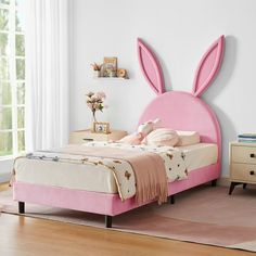 a pink bed with bunny ears on the headboard and foot board in a bedroom