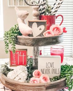 a three tiered tray with candles, flowers and other items on it for valentine's day