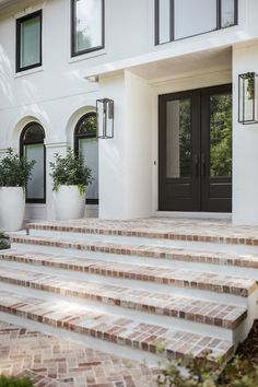 a white house with steps leading up to the front door and two large planters