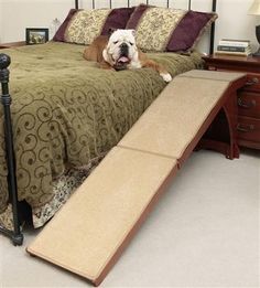 a dog laying on top of a bed with a ramp attached to the headboard