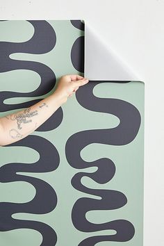 a man with tattoos on his arm is painting a wall in black and green colors