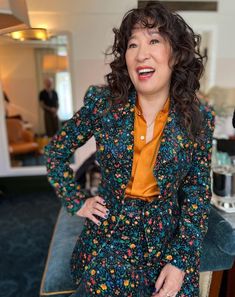 a woman standing in front of a mirror wearing a colorful suit and smiling at the camera