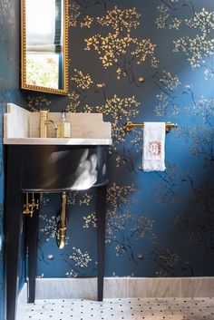 a sink and mirror in a room with blue wallpaper, gold trimmings