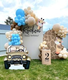 a car parked in front of a sign with balloons and giraffes on it