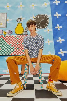 a young man sitting on top of a checkered floor