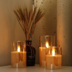 candles are lit in front of a mirror with wheat stalks on the table next to it