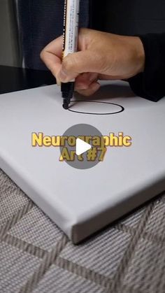 a person holding a pen and writing on a piece of paper with the words neuro graphic art 8 7