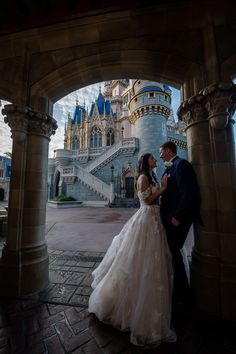 a bride and groom standing in front of a castle