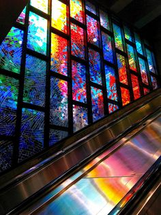 an escalator with colorful stained glass in the background