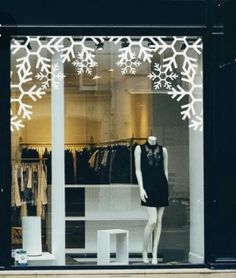 a mannequin in front of a store window with snowflakes on it