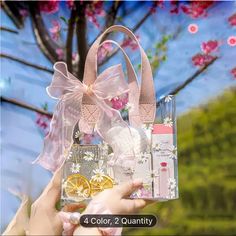 a person holding up a clear bag with flowers and other items in it that include perfumes