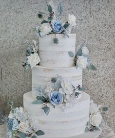 a white wedding cake with blue flowers and greenery