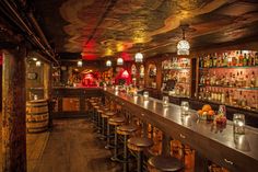 a long bar with stools and bottles on the shelves