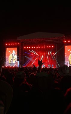 a concert scene with people on stage and one person raising their hands in the air