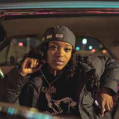 a woman sitting in the back seat of a car wearing a beanie and jacket